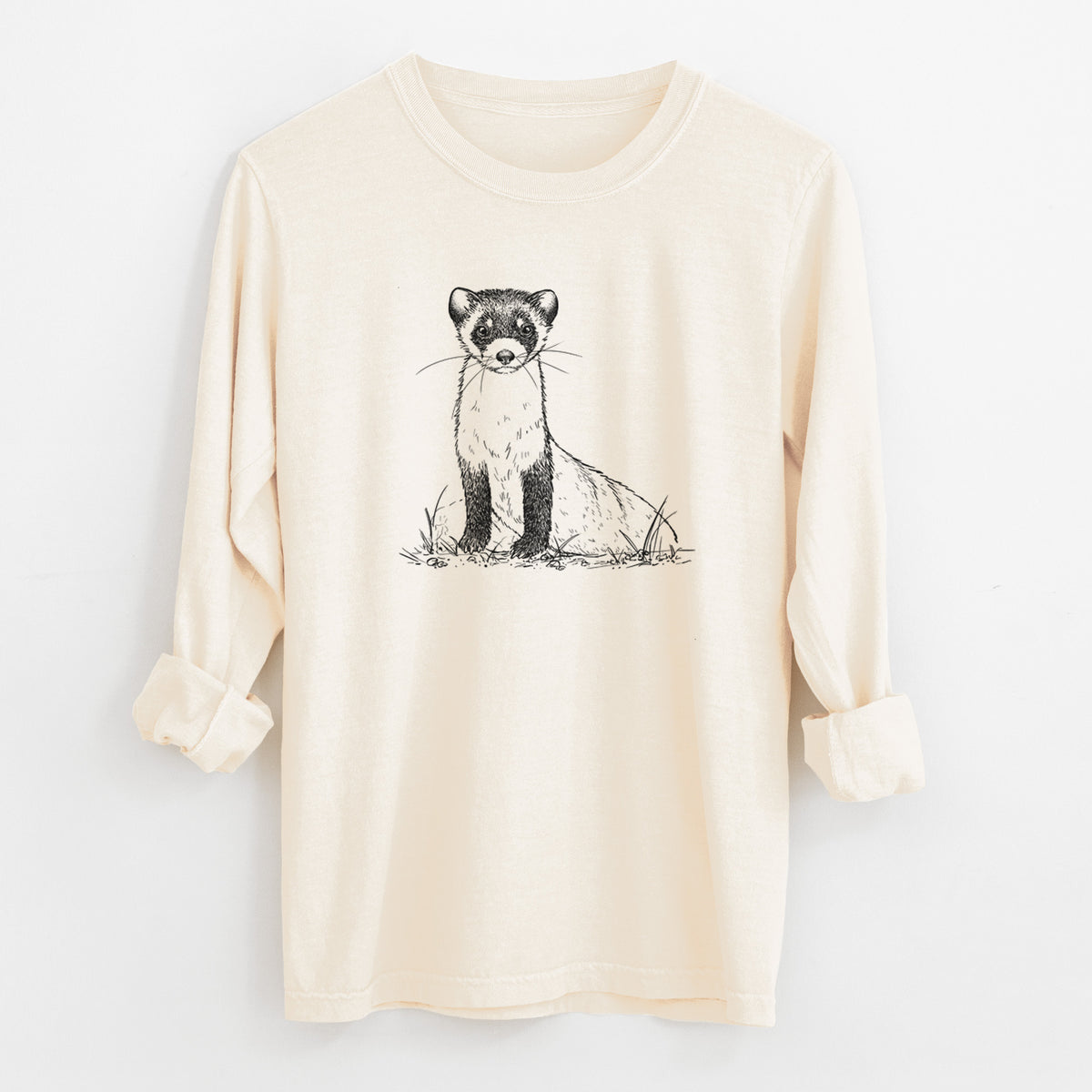 Ivory Comfort Colors long sleeve shirt laid flat with the cuffs rolled, printed with a detailed black ink illustration of a black-footed ferret sitting on the ground.