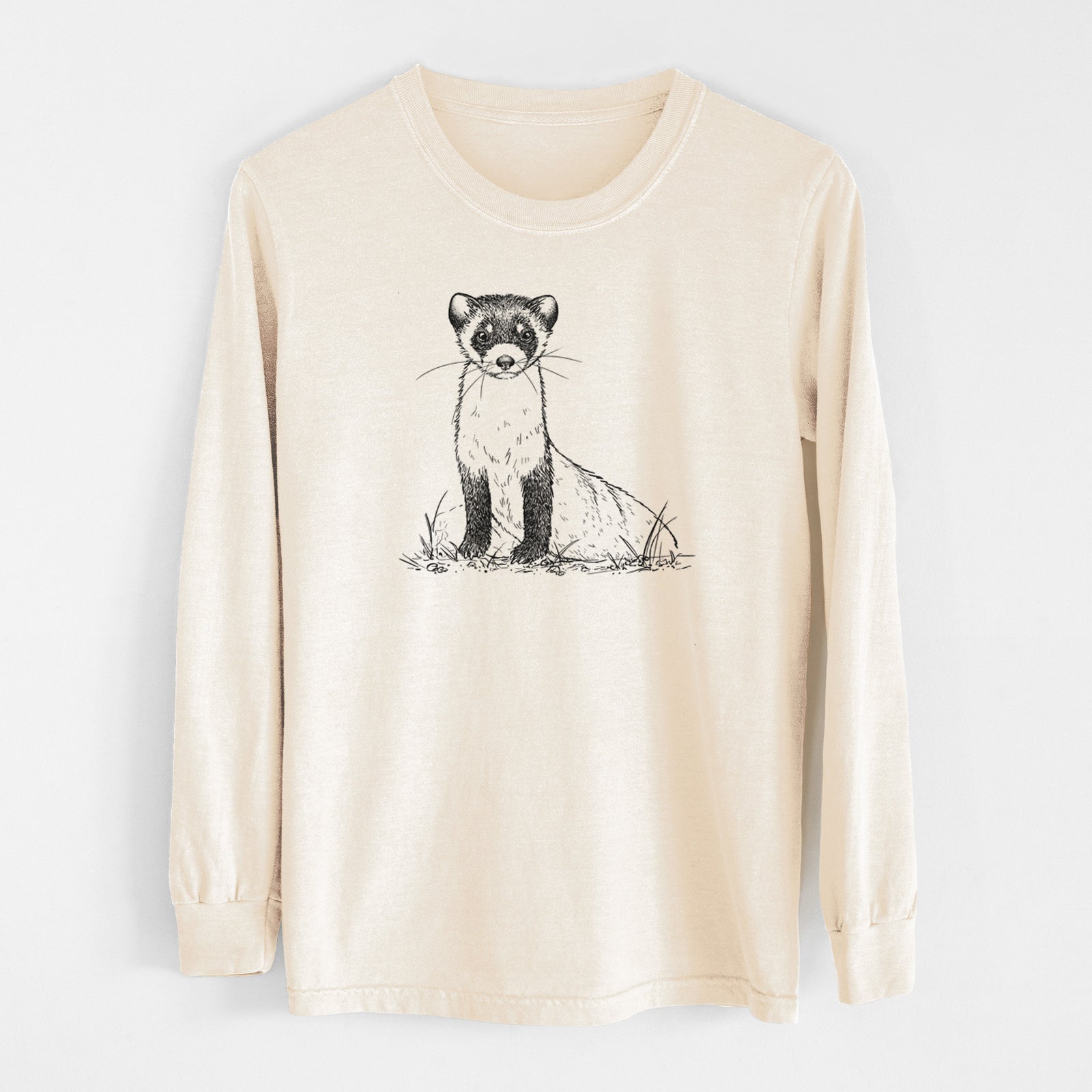 Ivory Comfort Colors long sleeve shirt laid flat, printed with a detailed black ink illustration of a black-footed ferret sitting on the ground.