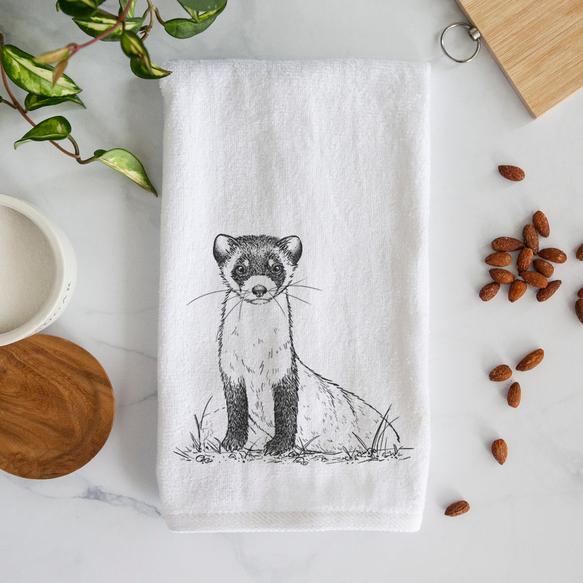 White hand towel printed with a detailed black ink illustration of a black-footed ferret sitting on the ground.