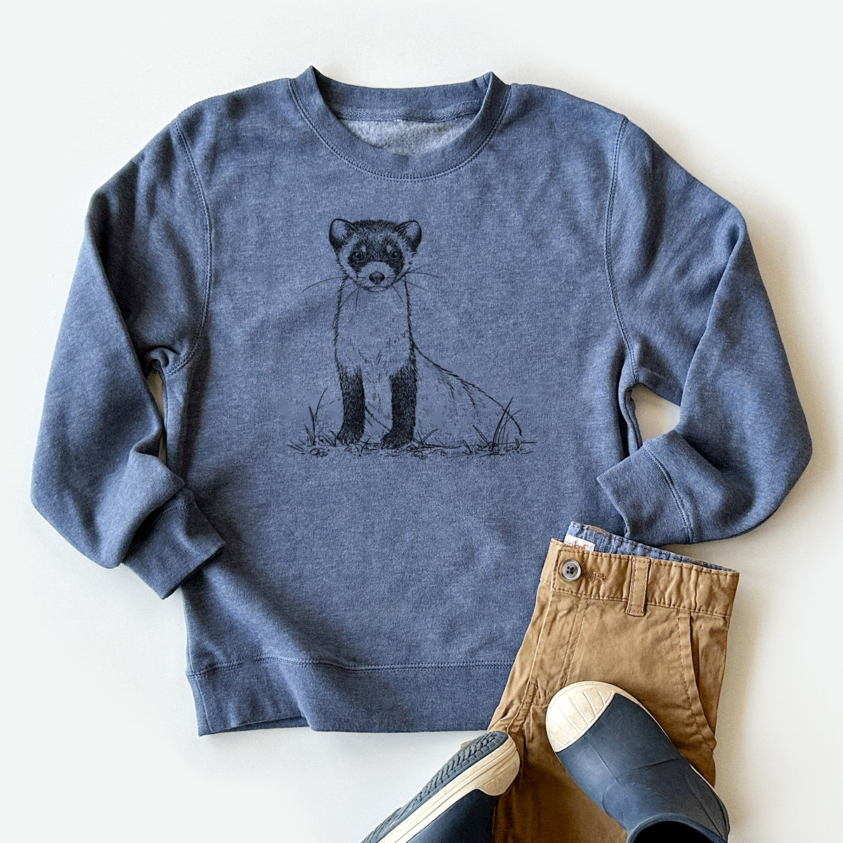 Youth crewneck sweatshirt printed with a detailed black ink illustration of a black-footed ferret sitting on the ground, styled flat with khaki pants and shoes.