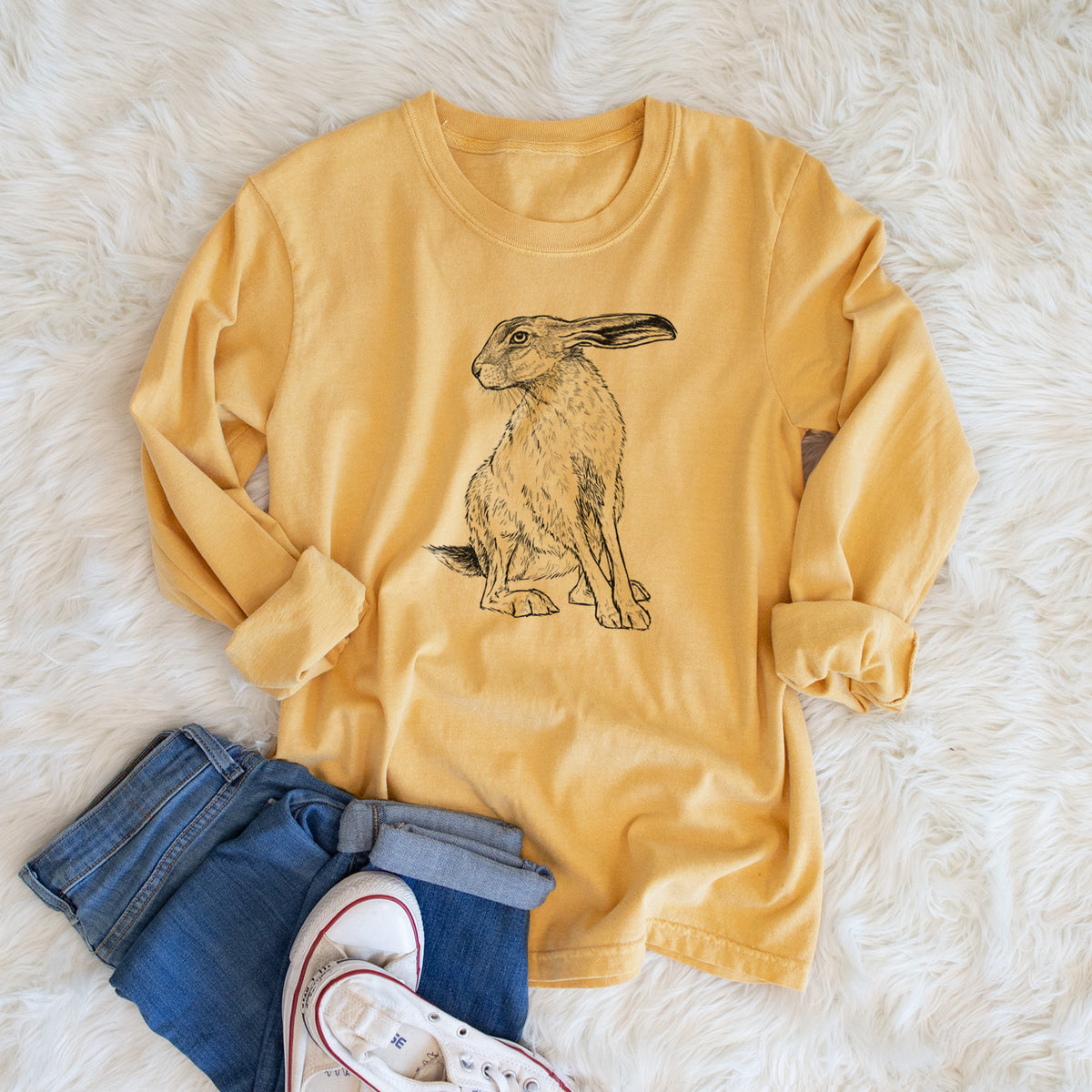 Golden wheat yellow Comfort Colors long sleeve shirt printed with a detailed black ink illustration of a black-tailed jackrabbit sitting with long upright ears, shown in a lifestyle photo.