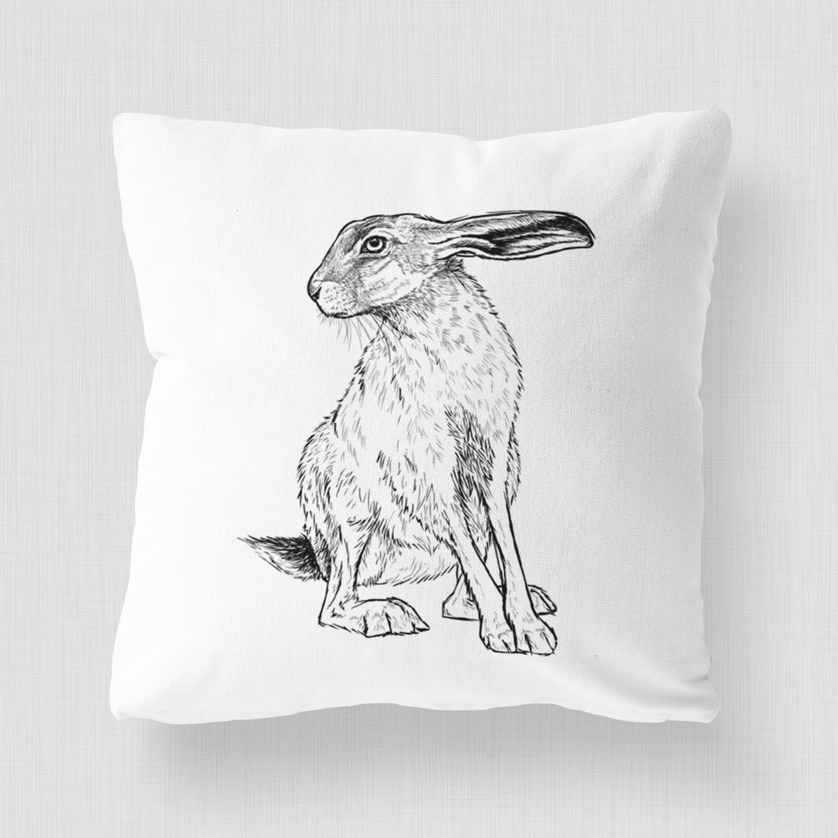 White pillow cover printed with a detailed black ink illustration of a black-tailed jackrabbit sitting with long upright ears.