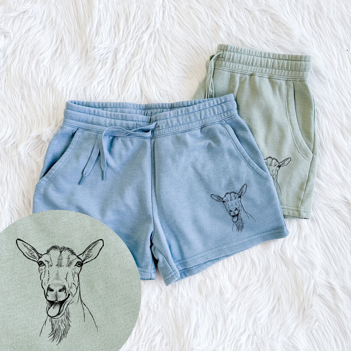 Two pairs of Cali Wave shorts in different colors printed with a black ink illustration of a goat's head with its mouth open mid-bleat and its tongue out, with a close-up of the print.