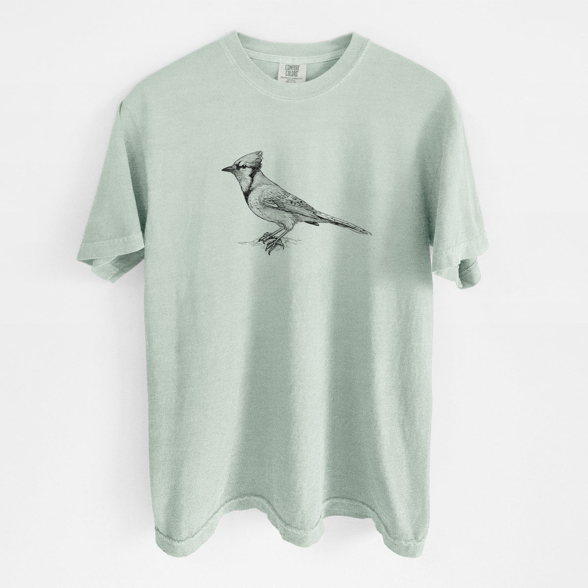 Bay green Comfort Colors t-shirt laid flat, printed with a detailed black ink sketch of a blue jay perched with its crest raised.
