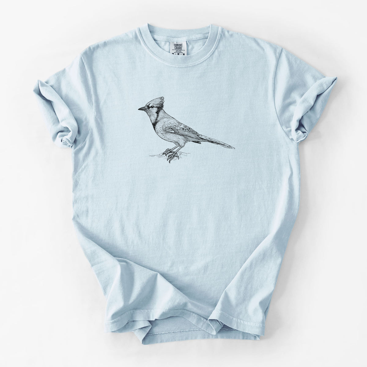 Chambray blue Comfort Colors t-shirt laid flat, printed with a detailed black ink sketch of a blue jay perched with its crest raised.