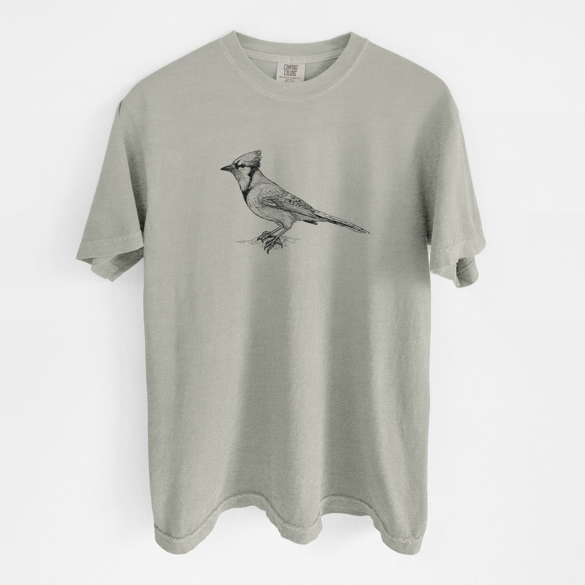 Sandstone beige Comfort Colors t-shirt laid flat, printed with a detailed black ink sketch of a blue jay perched with its crest raised.