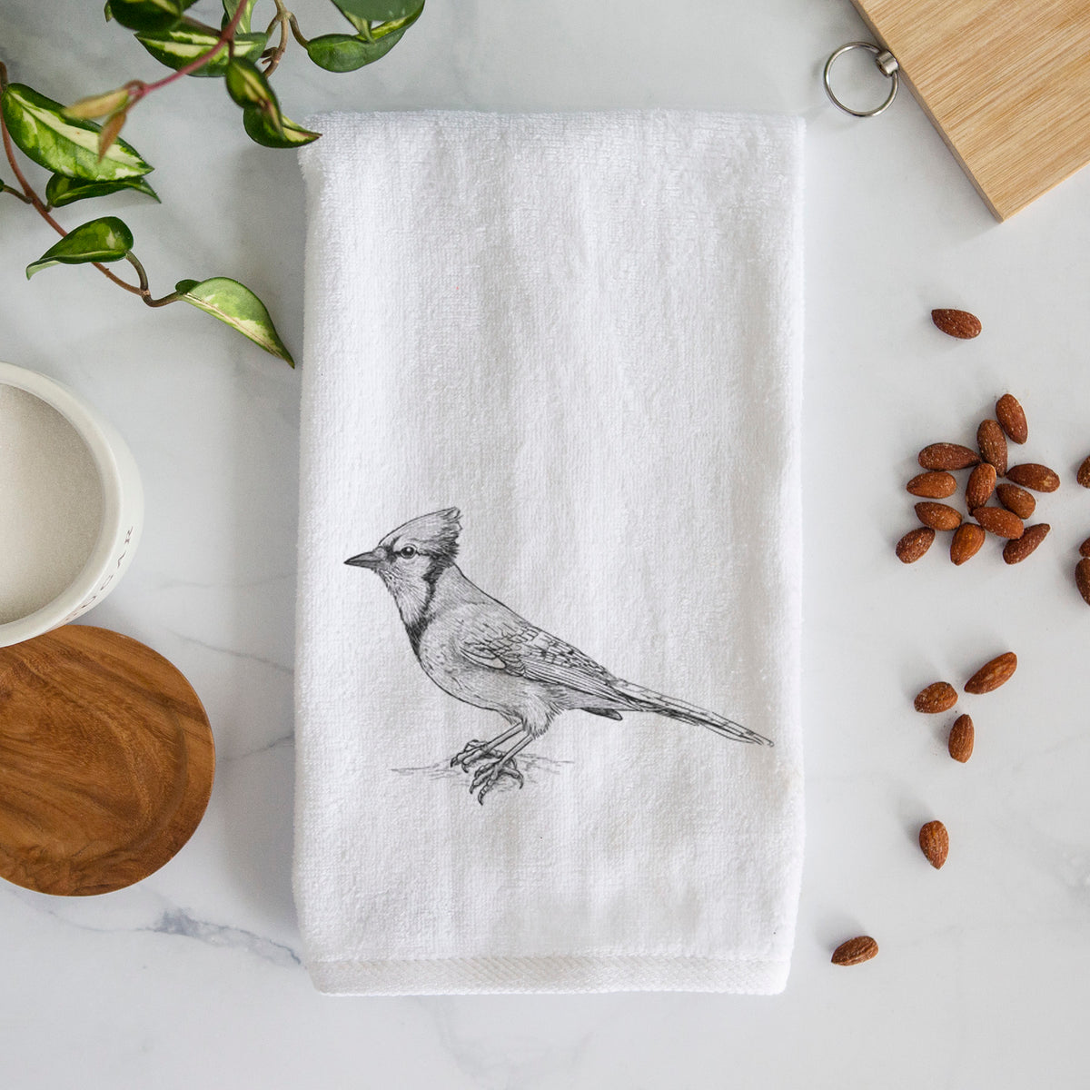 White hand towel printed with a detailed black ink sketch of a blue jay perched with its crest raised.