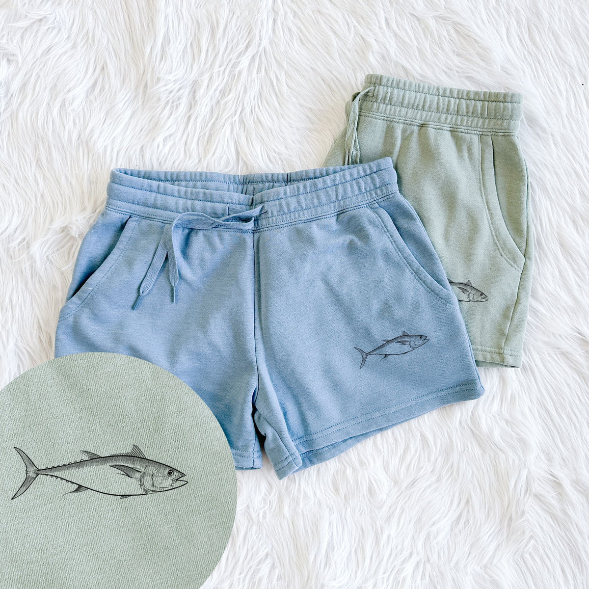 Two pairs of Cali Wave shorts in different colors printed with a black ink line drawing of a bluefin tuna swimming, with a close-up of the print.