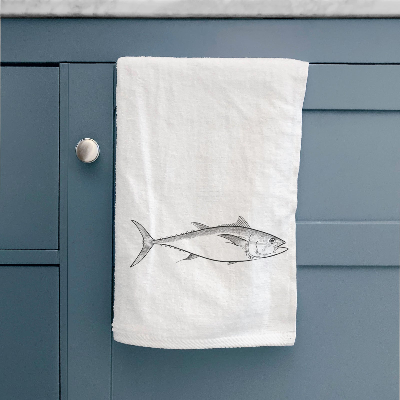 White hand towel printed with a black ink line drawing of a bluefin tuna swimming.