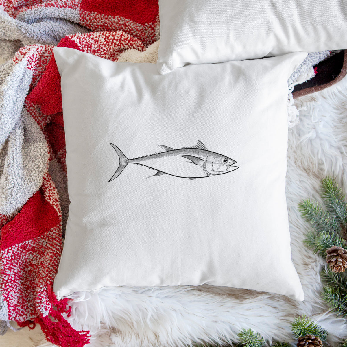 White pillow cover printed with a black ink line drawing of a bluefin tuna swimming, on a woven chair.
