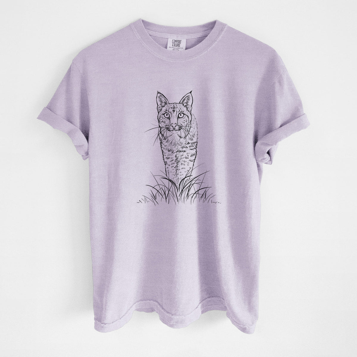 Orchid purple Comfort Colors t-shirt laid flat, printed with a black ink illustration of a bobcat standing in tall grass, facing forward.