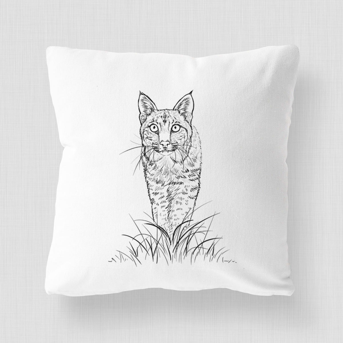 White pillow cover printed with a black ink illustration of a bobcat standing in tall grass, facing forward.
