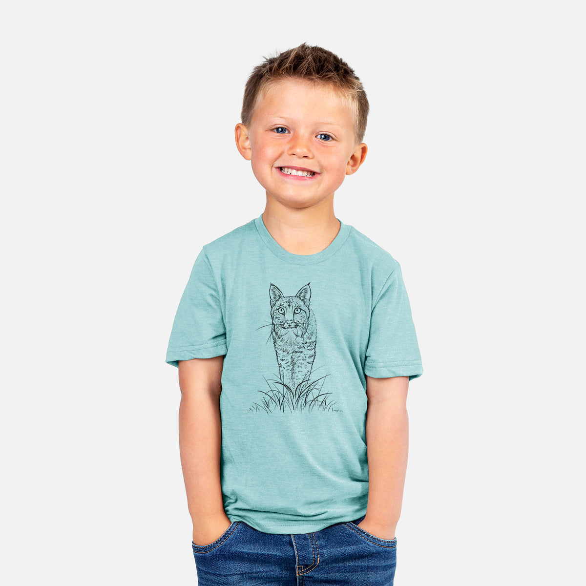 Smiling boy wearing a youth t-shirt printed with a black ink illustration of a bobcat standing in tall grass, facing forward.