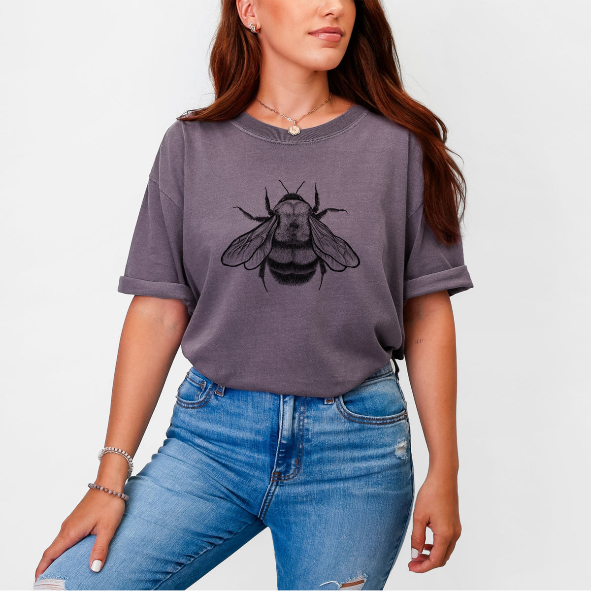 Woman wearing a Comfort Colors t-shirt printed with a detailed black ink illustration of a rusty patched bumble bee with its wings spread, seen from above.