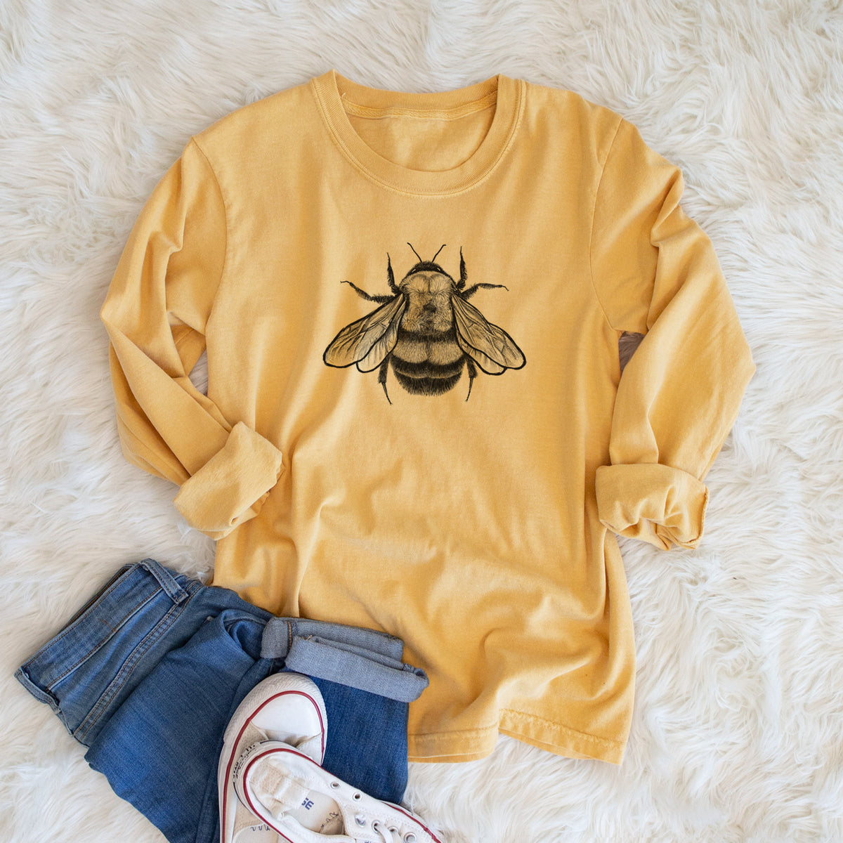 Golden wheat yellow Comfort Colors long sleeve shirt printed with a detailed black ink illustration of a rusty patched bumble bee with its wings spread, seen from above, shown in a lifestyle photo.