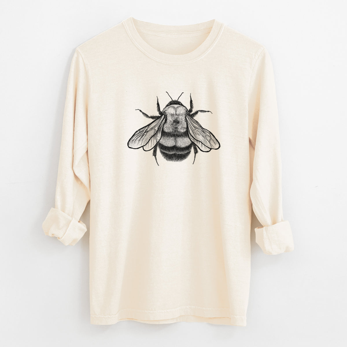 Ivory Comfort Colors long sleeve shirt laid flat with the cuffs rolled, printed with a detailed black ink illustration of a rusty patched bumble bee with its wings spread, seen from above.