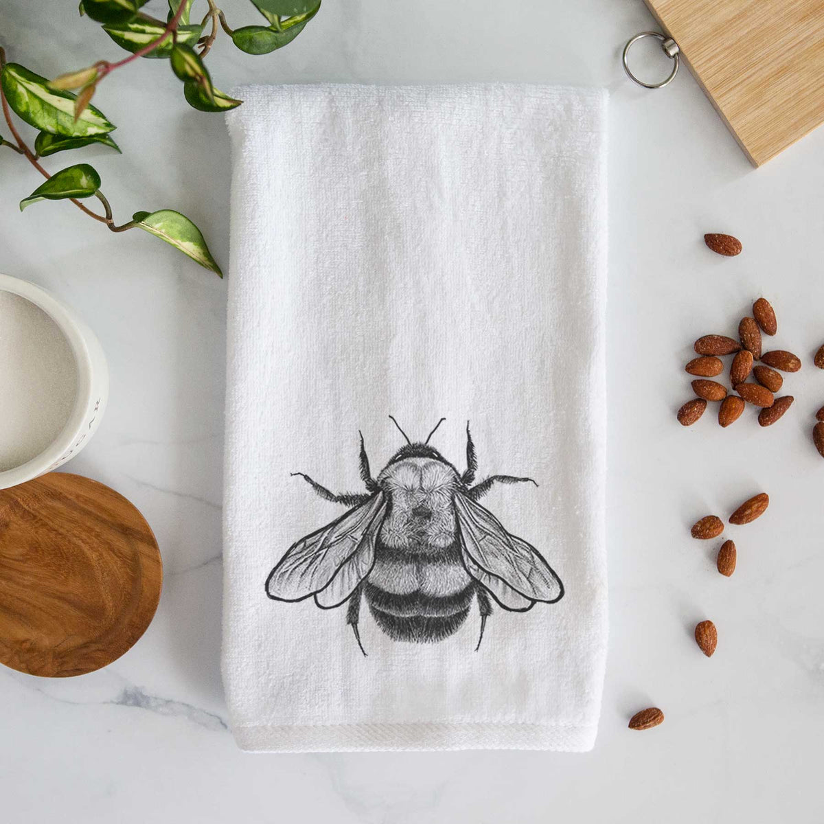 White hand towel printed with a detailed black ink illustration of a rusty patched bumble bee with its wings spread, seen from above.