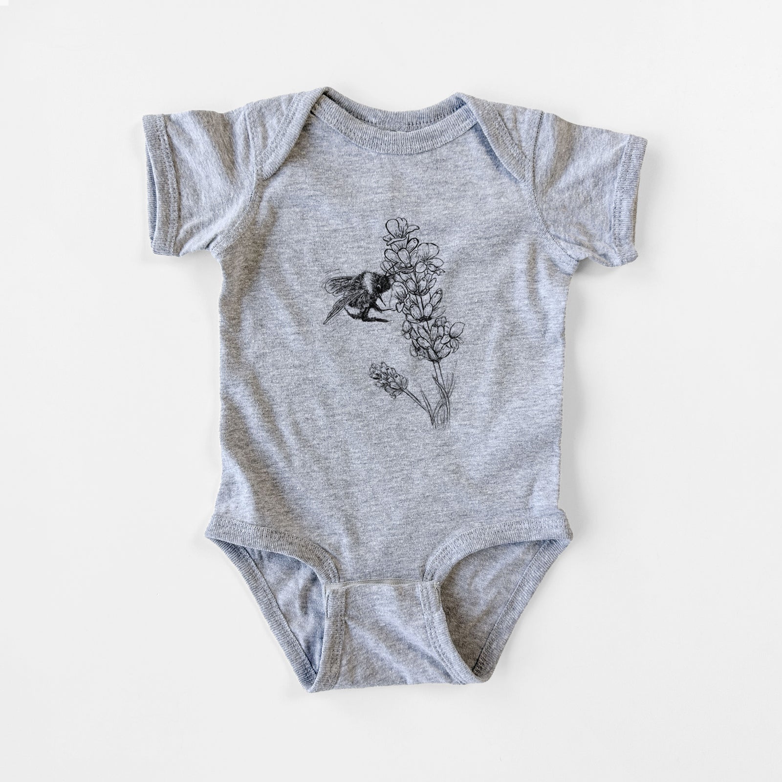 Grey baby bodysuit laid flat, printed with a black ink illustration of a bumble bee visiting a sprig of lavender.