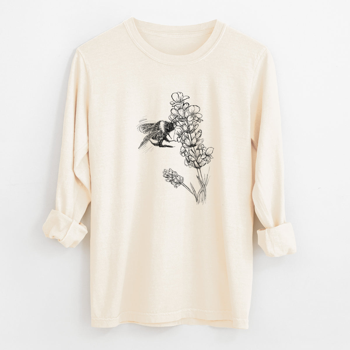Ivory Comfort Colors long sleeve shirt laid flat with the cuffs rolled, printed with a black ink illustration of a bumble bee visiting a sprig of lavender.
