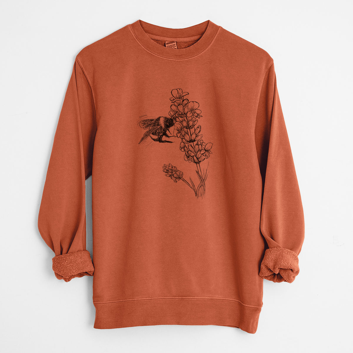 Amber orange pigment dyed crewneck sweatshirt laid flat with the sleeves rolled, printed with a black ink illustration of a bumble bee visiting a sprig of lavender.