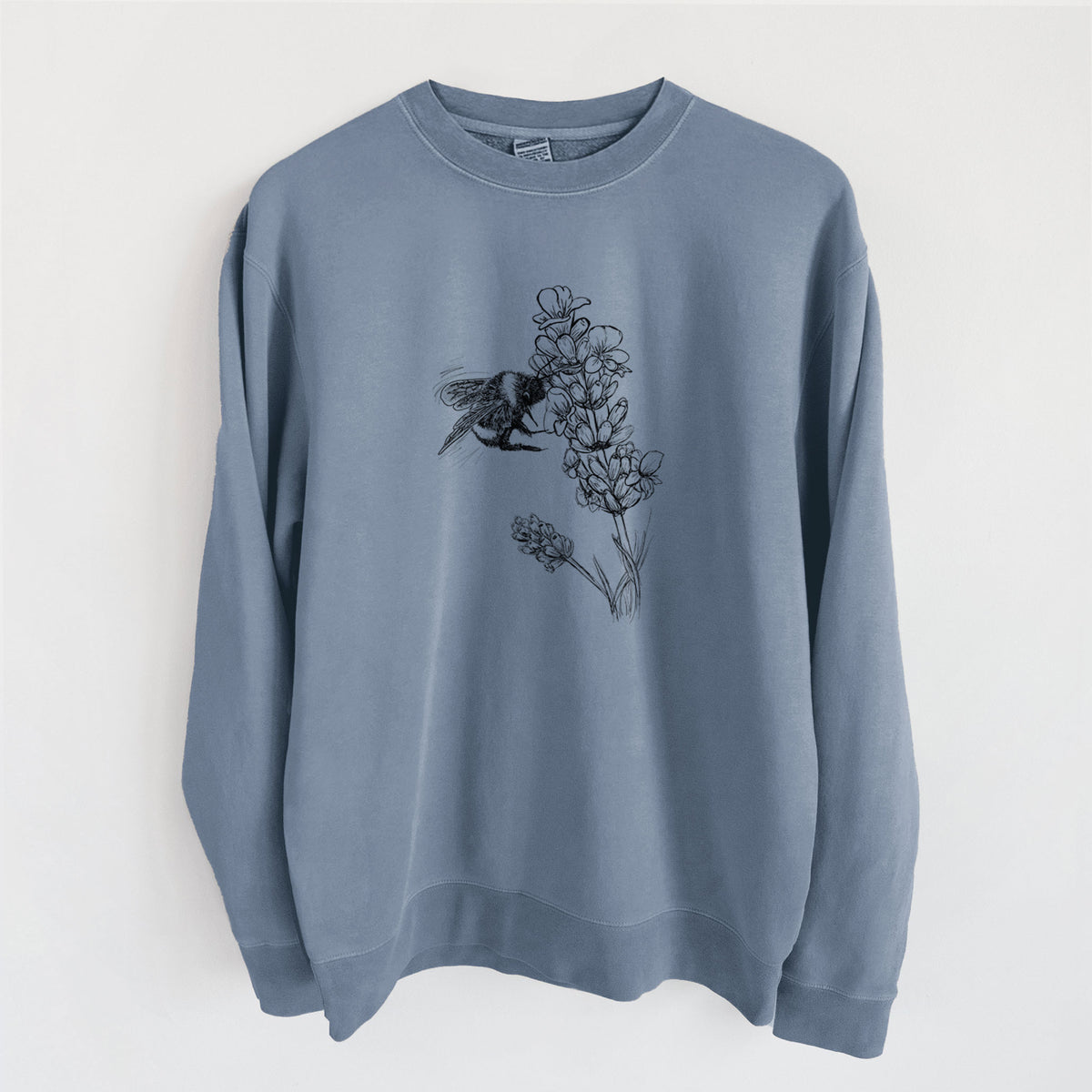 Slate blue pigment dyed crewneck sweatshirt laid flat, printed with a black ink illustration of a bumble bee visiting a sprig of lavender.