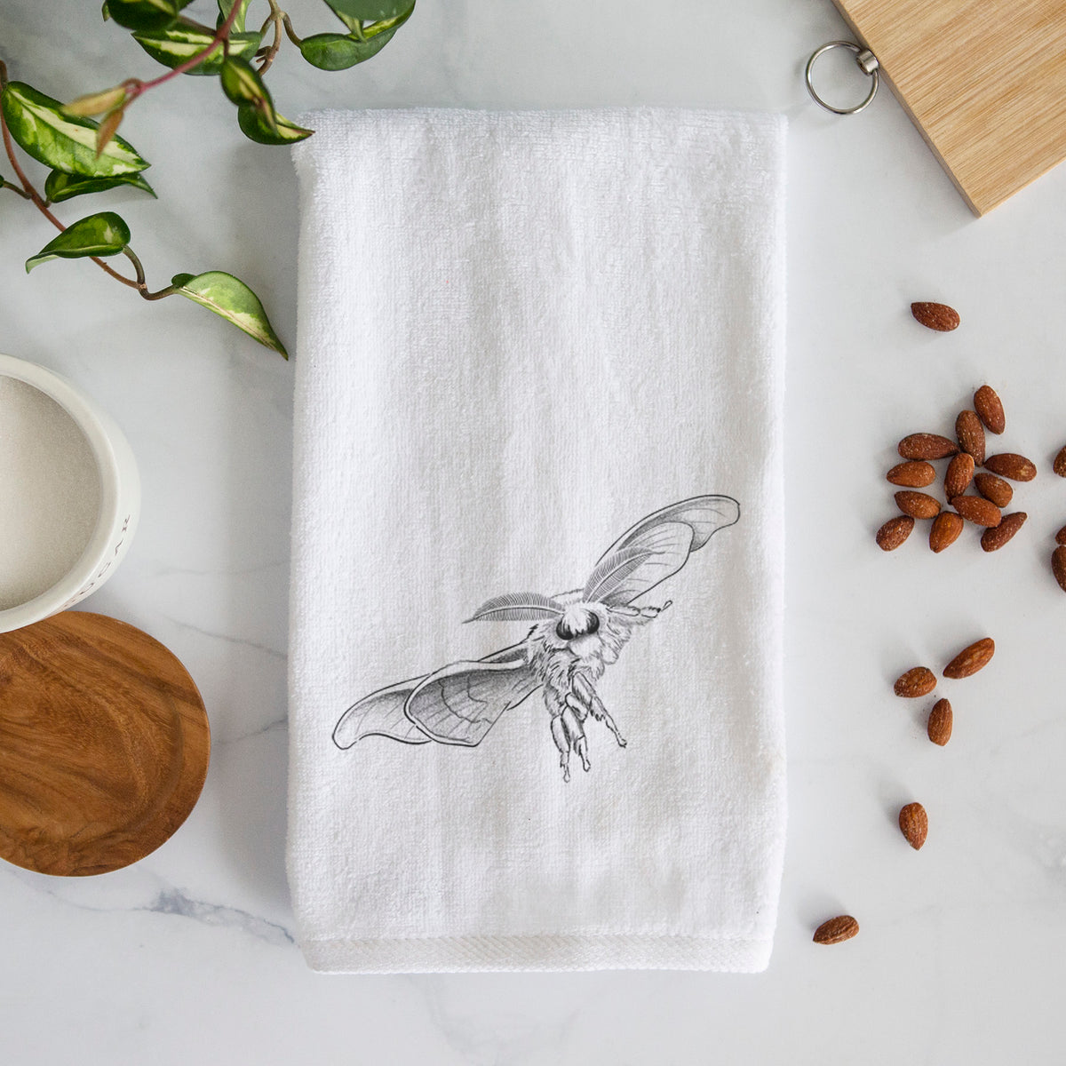 White hand towel printed with a black ink illustration of a silk moth with its wings spread.