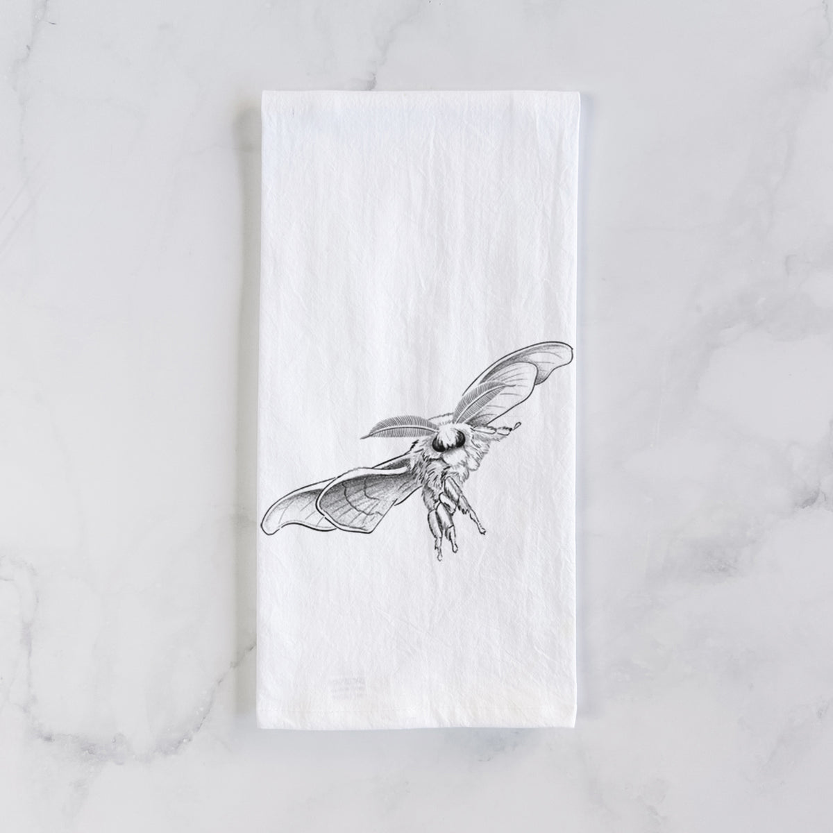 White cotton tea towel laid flat on marble, printed with a black ink illustration of a silk moth with its wings spread.
