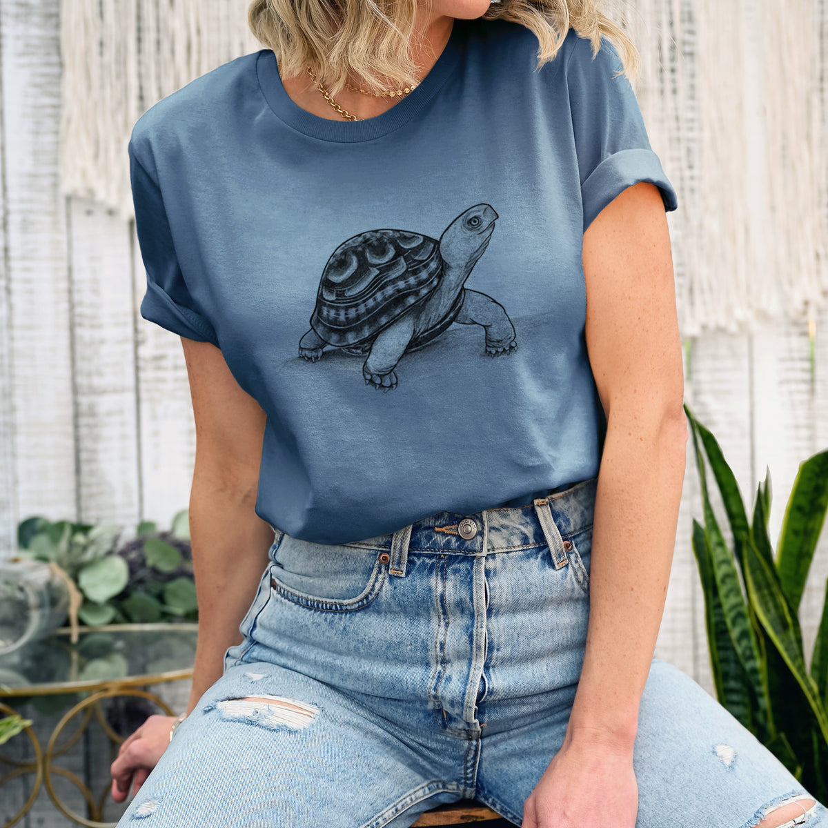 Woman wearing a steel blue lightweight cotton t-shirt printed with a detailed black ink illustration of an eastern box turtle walking.