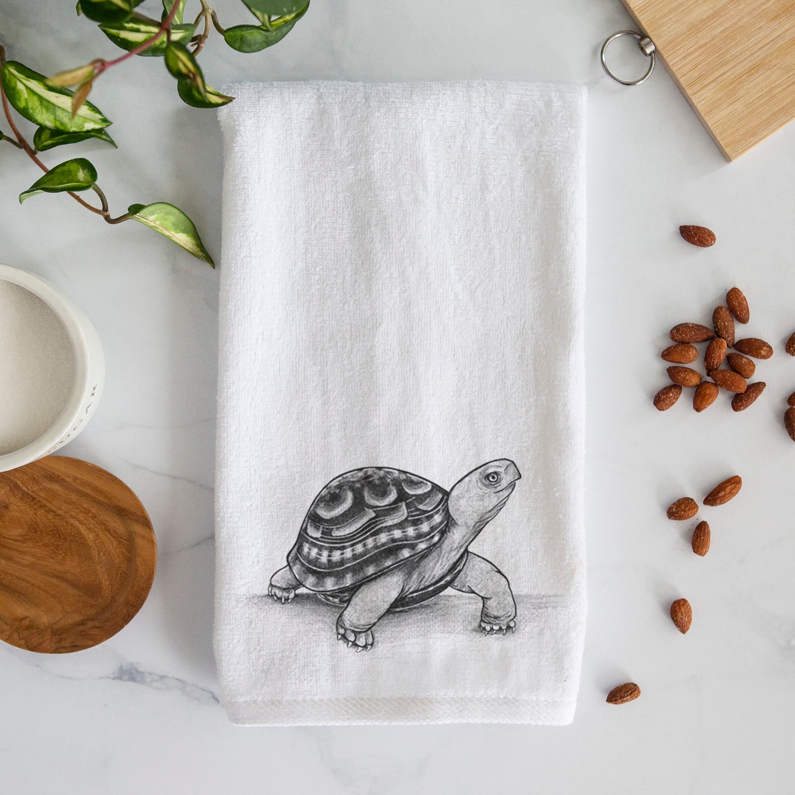 White hand towel printed with a detailed black ink illustration of an eastern box turtle walking.