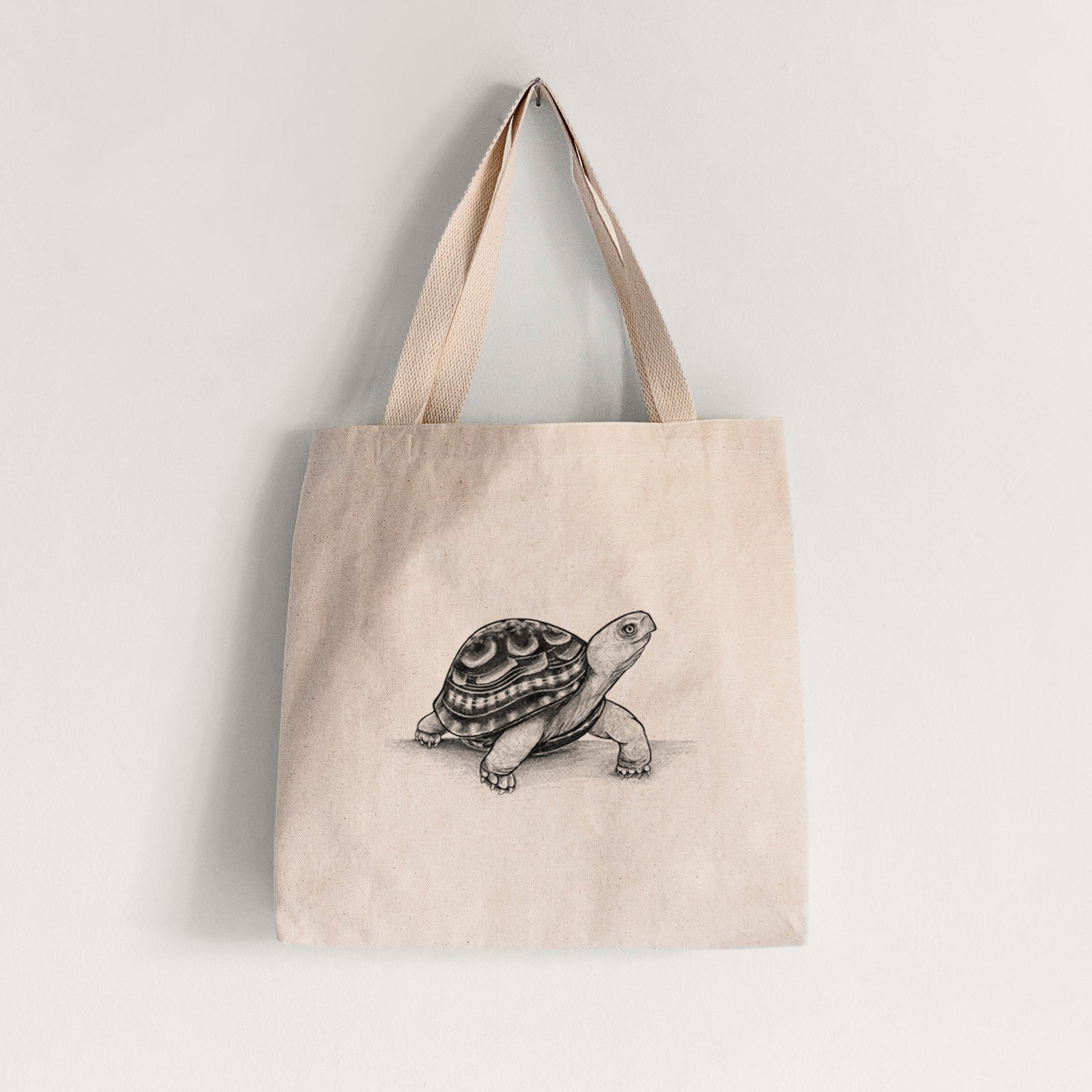 Natural canvas tote bag printed with a detailed black ink illustration of an eastern box turtle walking.