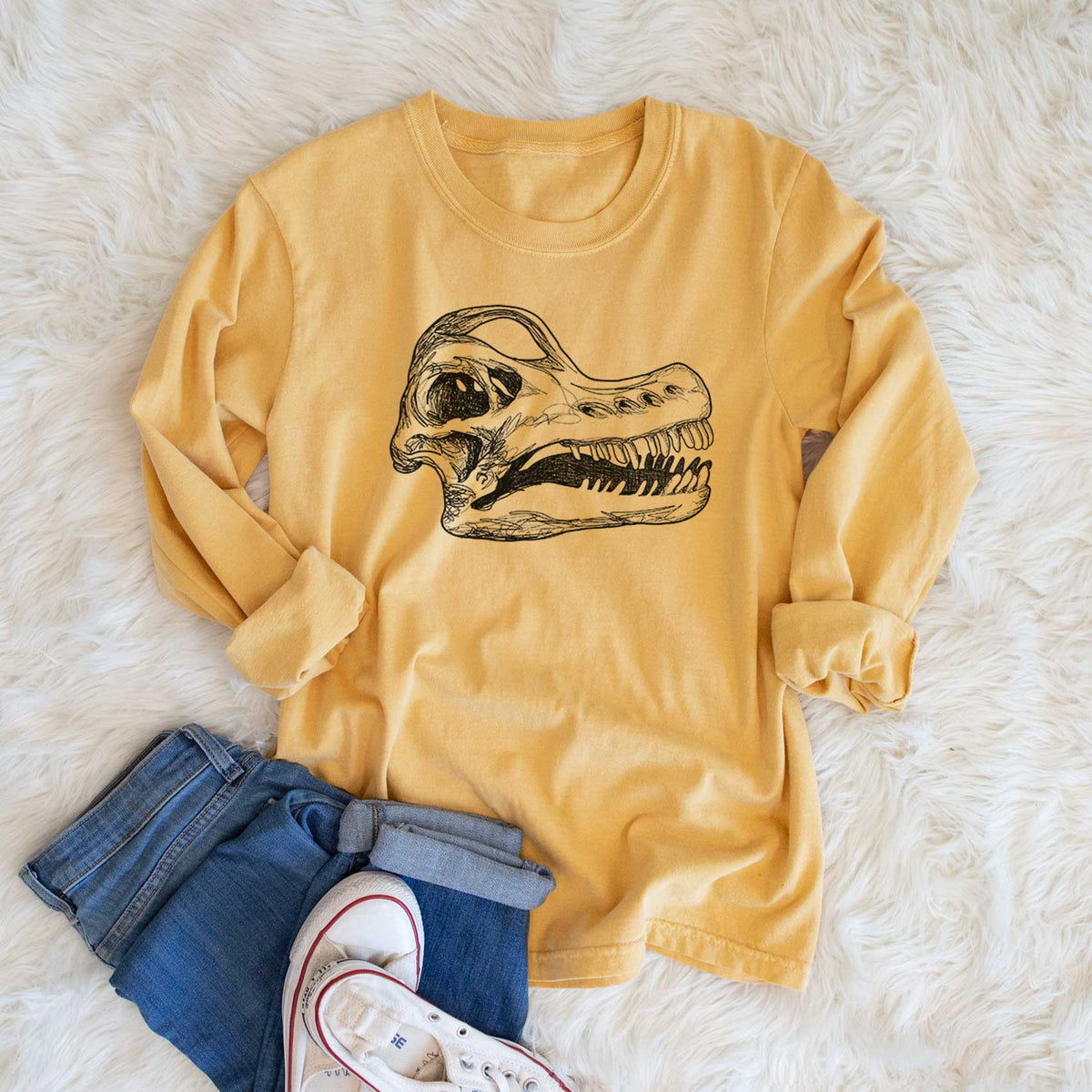 Golden wheat yellow Comfort Colors long sleeve shirt printed with a detailed black ink illustration of a Brachiosaurus skull, shown in a lifestyle photo.