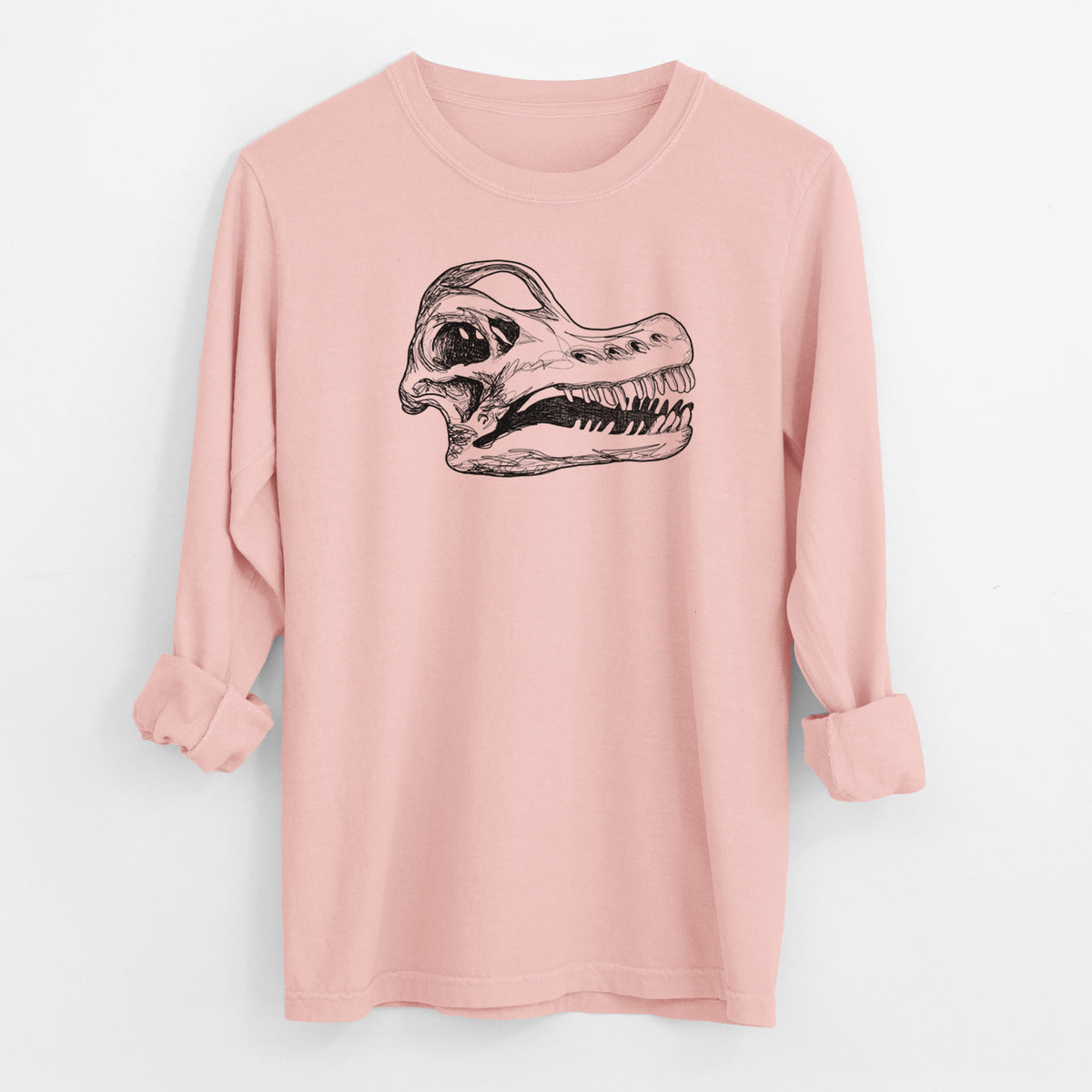 Peachy Comfort Colors long sleeve shirt laid flat with the cuffs rolled, printed with a detailed black ink illustration of a Brachiosaurus skull.