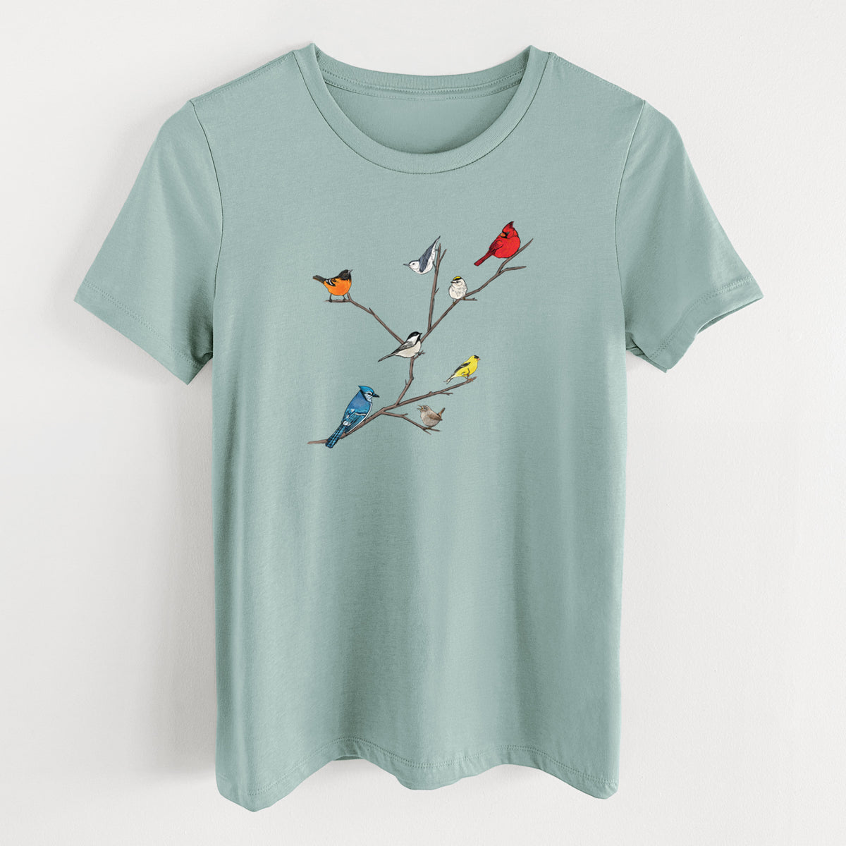 Dusty blue women's relaxed fit cotton t-shirt laid flat, printed with a full-color illustration of backyard birds, including a cardinal, blue jay, goldfinch and robin, perched on bare branches.