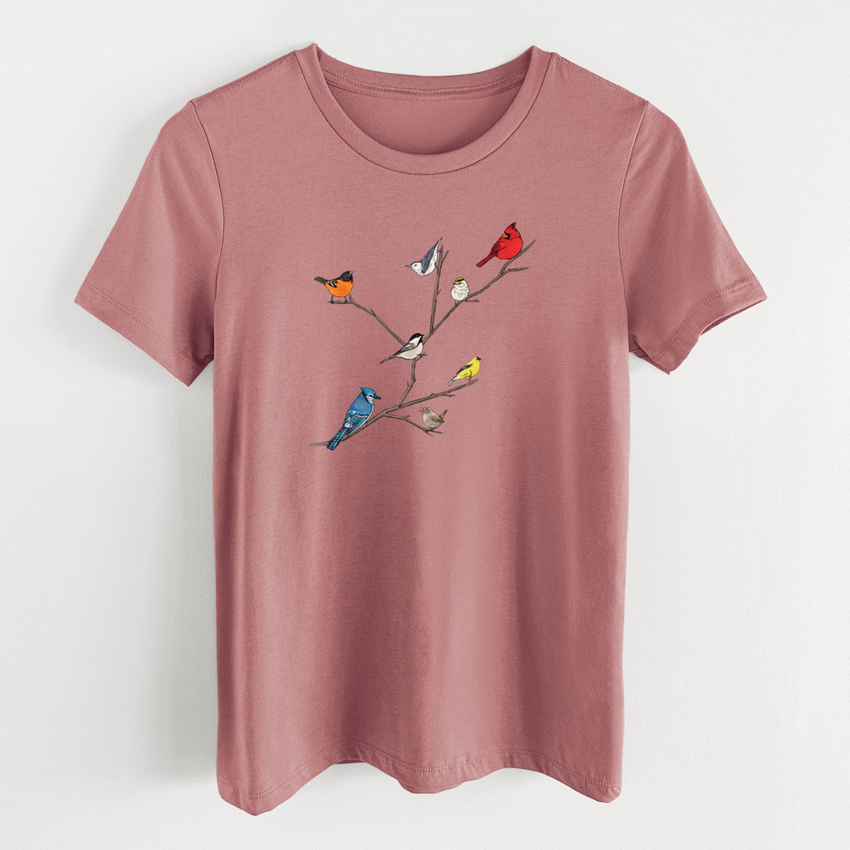 Mauve pink women's relaxed fit cotton t-shirt laid flat, printed with a full-color illustration of backyard birds, including a cardinal, blue jay, goldfinch and robin, perched on bare branches.