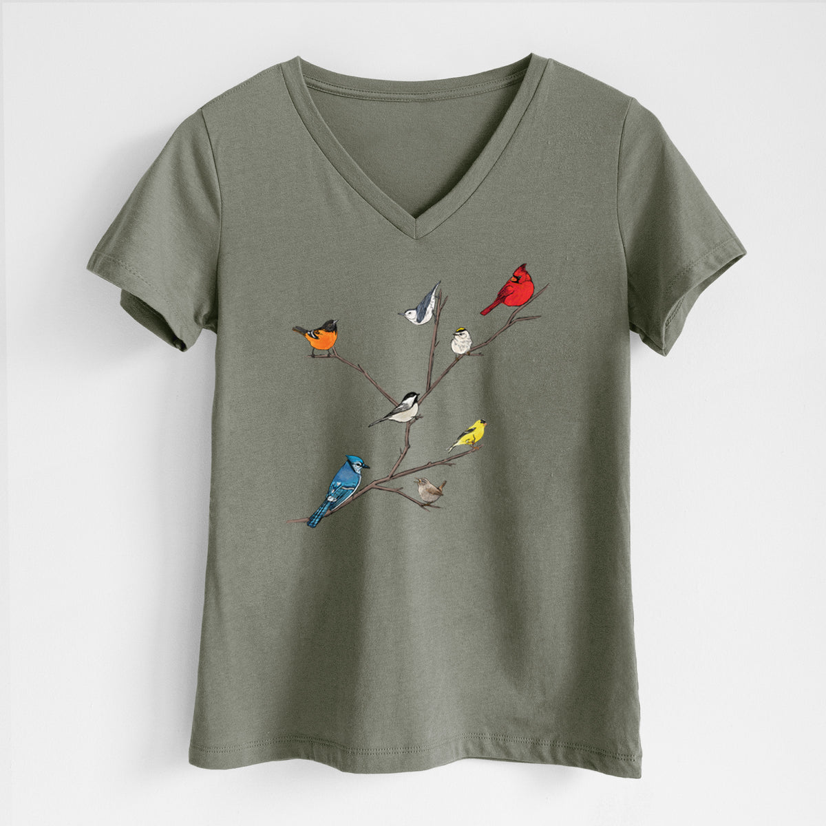 Military green women's relaxed fit cotton V-neck t-shirt laid flat, printed with a full-color illustration of backyard birds, including a cardinal, blue jay, goldfinch and robin, perched on bare branches.