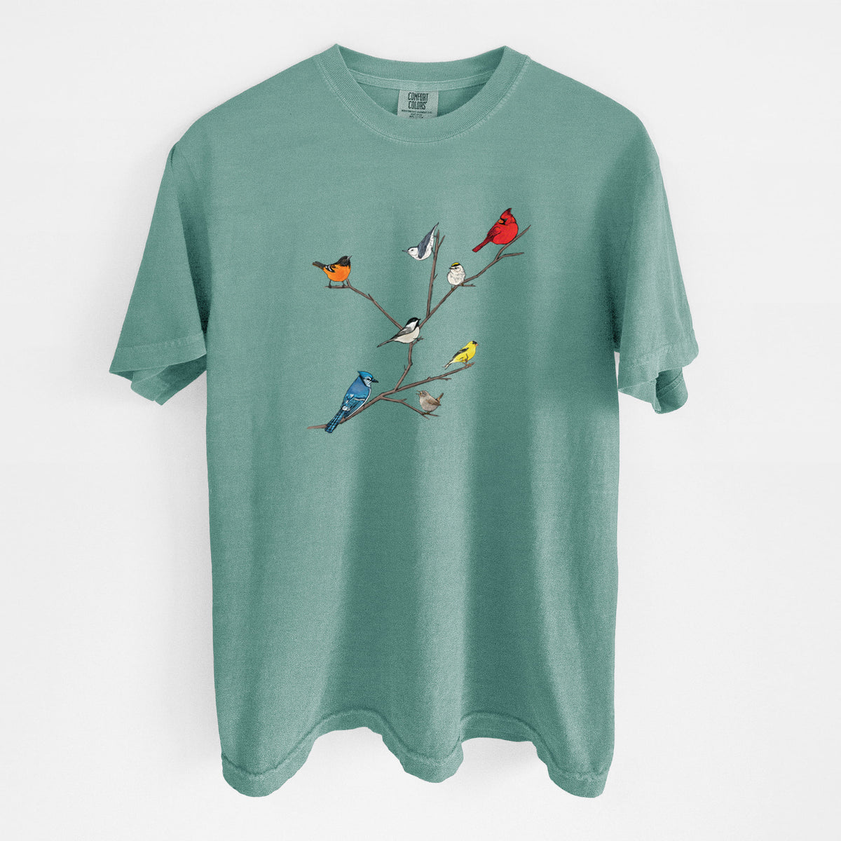 Reef green Comfort Colors t-shirt laid flat, printed with a full-color illustration of backyard birds, including a cardinal, blue jay, goldfinch and robin, perched on bare branches.