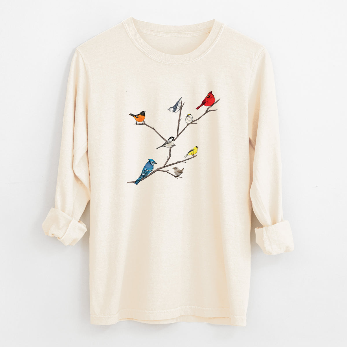 Ivory Comfort Colors long sleeve shirt laid flat with the cuffs rolled, printed with a full-color illustration of backyard birds, including a cardinal, blue jay, goldfinch and robin, perched on bare branches.