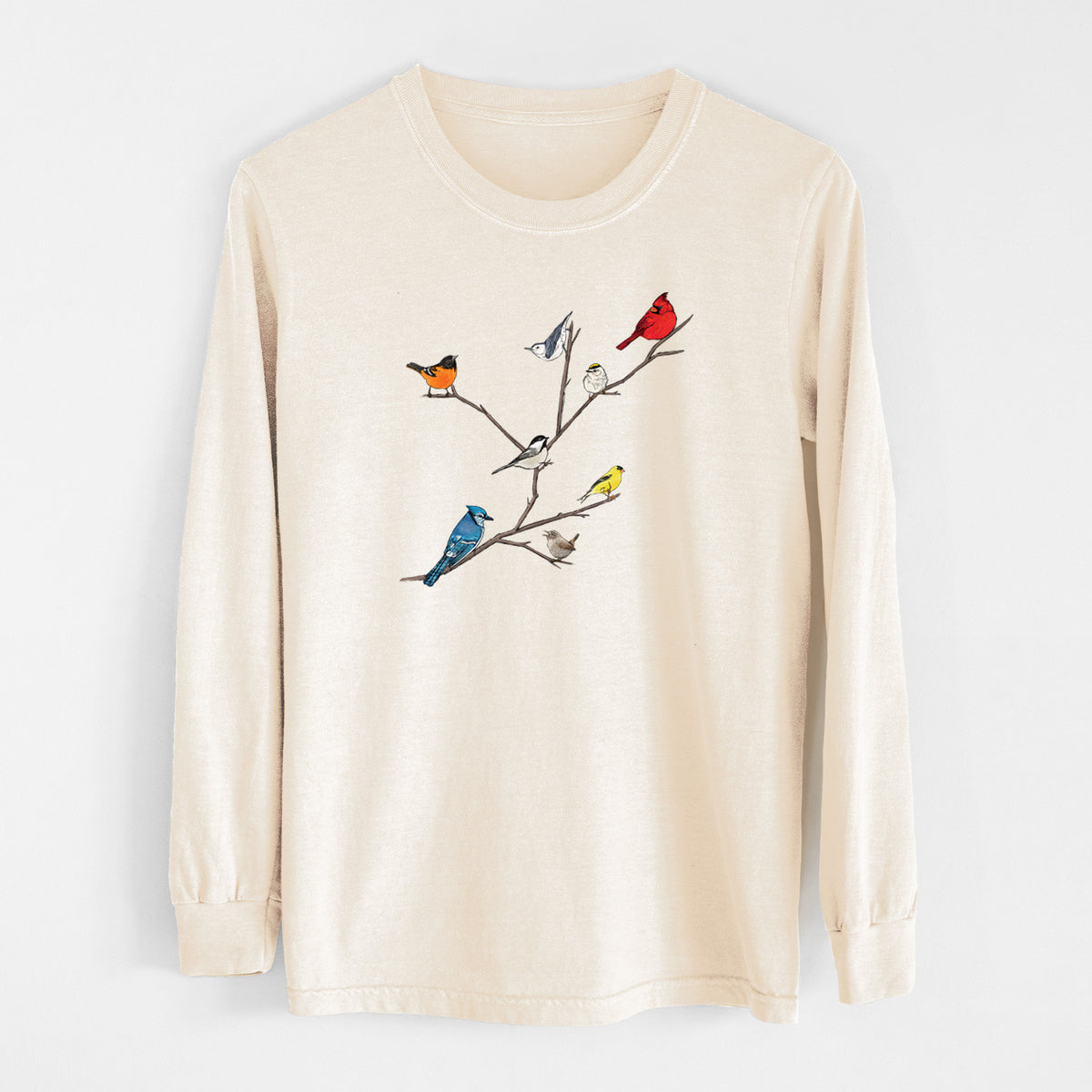 Ivory Comfort Colors long sleeve shirt laid flat, printed with a full-color illustration of backyard birds, including a cardinal, blue jay, goldfinch and robin, perched on bare branches.