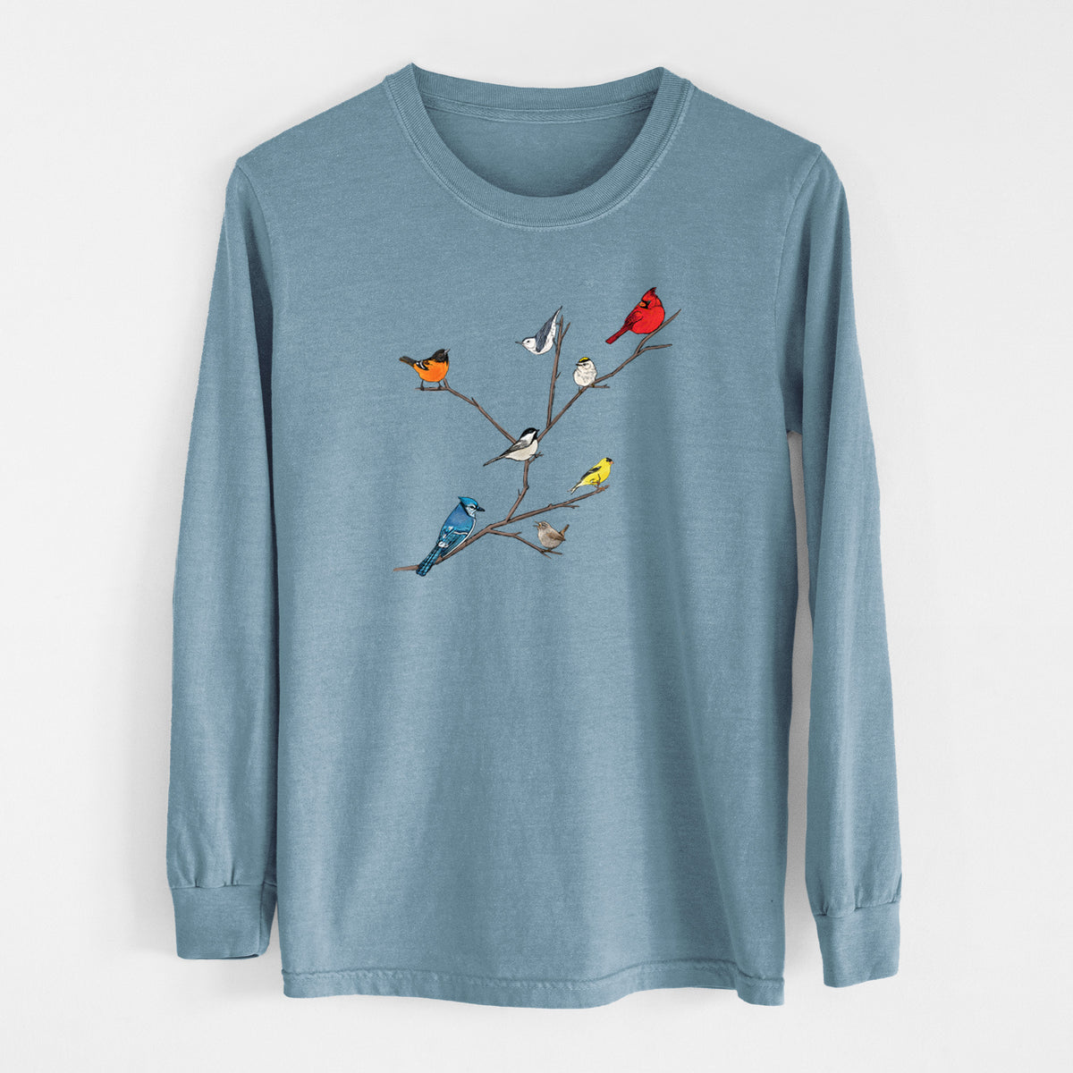 Steel blue Comfort Colors long sleeve shirt laid flat, printed with a full-color illustration of backyard birds, including a cardinal, blue jay, goldfinch and robin, perched on bare branches.