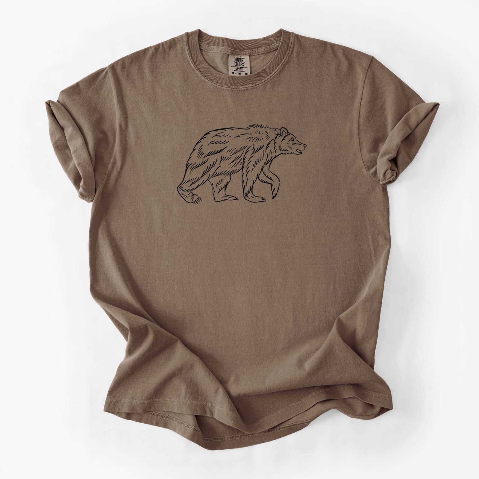 Blue jean Comfort Colors t-shirt laid flat, printed with a black ink illustration of a brown bear walking.