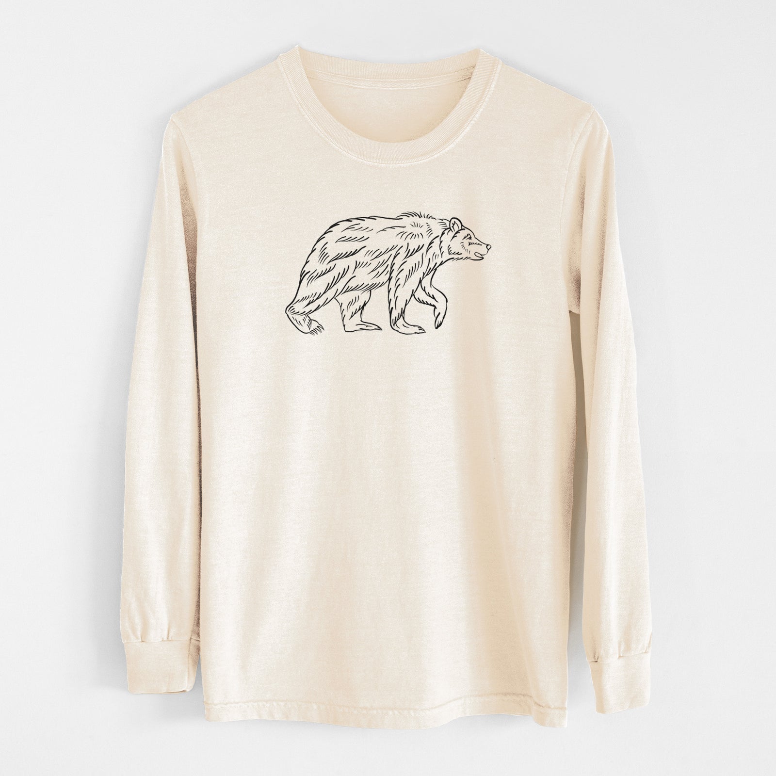 Ivory Comfort Colors long sleeve shirt laid flat, printed with a black ink illustration of a brown bear walking.