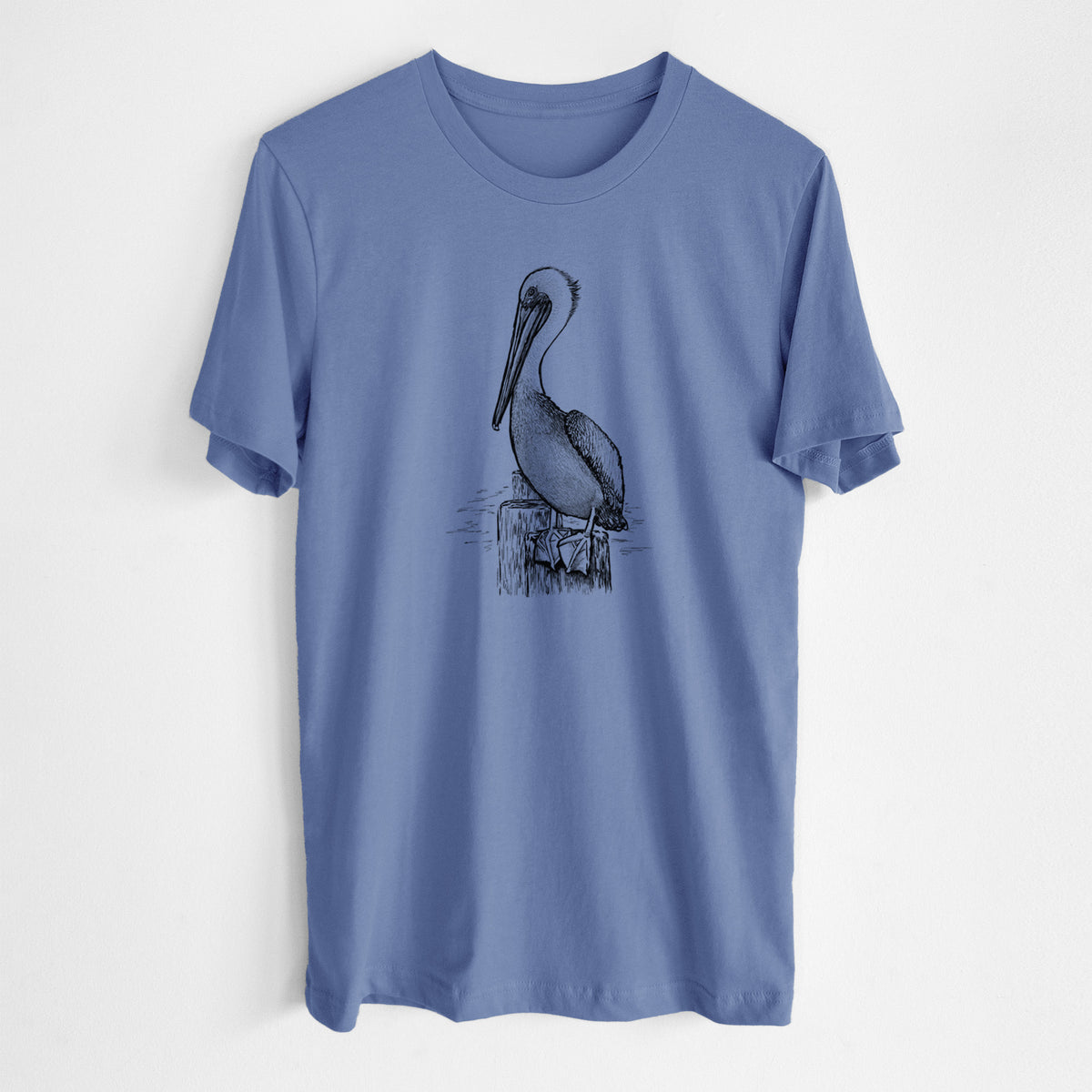 Blue bell lightweight cotton t-shirt laid flat, printed with a detailed black ink illustration of a brown pelican perched on a wooden piling.