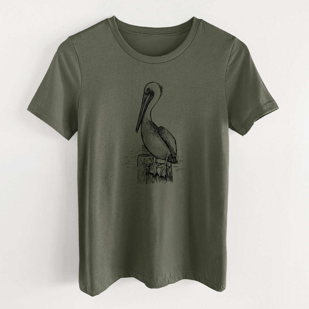 Military green women's relaxed fit cotton t-shirt laid flat, printed with a detailed black ink illustration of a brown pelican perched on a wooden piling.