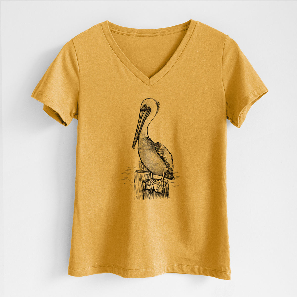 Honeycomb yellow women's relaxed fit cotton V-neck t-shirt laid flat, printed with a detailed black ink illustration of a brown pelican perched on a wooden piling.