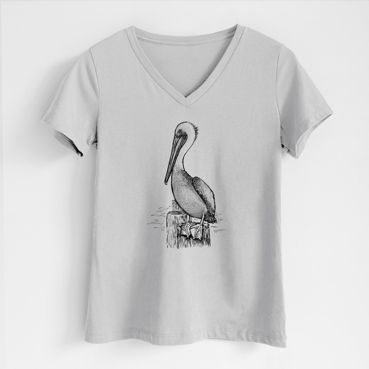 Lunar grey women's relaxed fit cotton V-neck t-shirt laid flat, printed with a detailed black ink illustration of a brown pelican perched on a wooden piling.