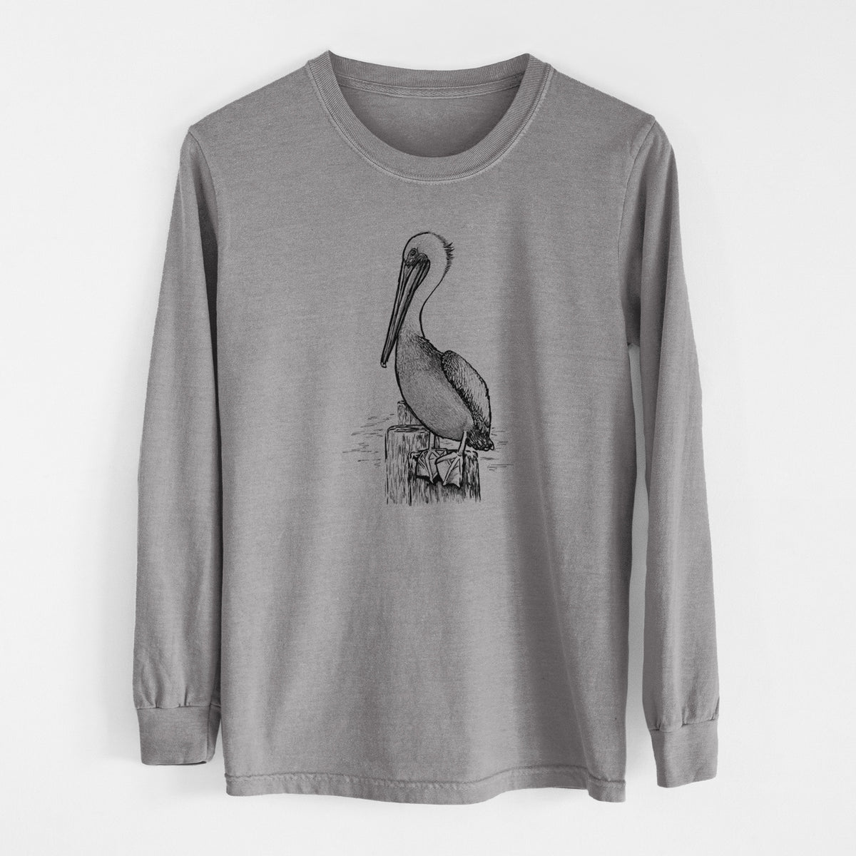 Grey Comfort Colors long sleeve shirt laid flat, printed with a detailed black ink illustration of a brown pelican perched on a wooden piling.