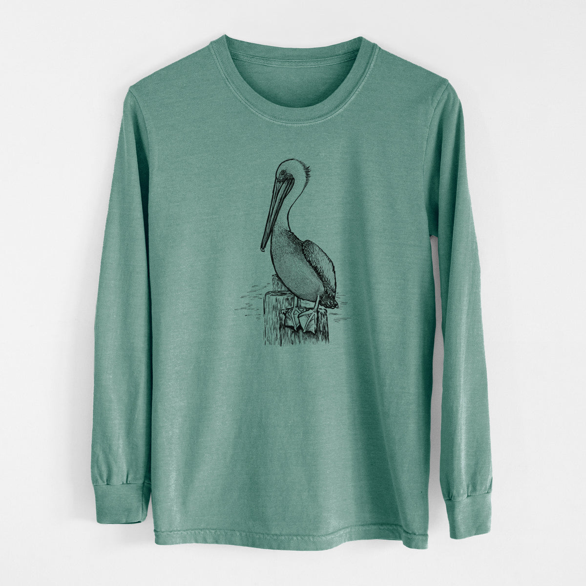 Pine green Comfort Colors long sleeve shirt laid flat, printed with a detailed black ink illustration of a brown pelican perched on a wooden piling.