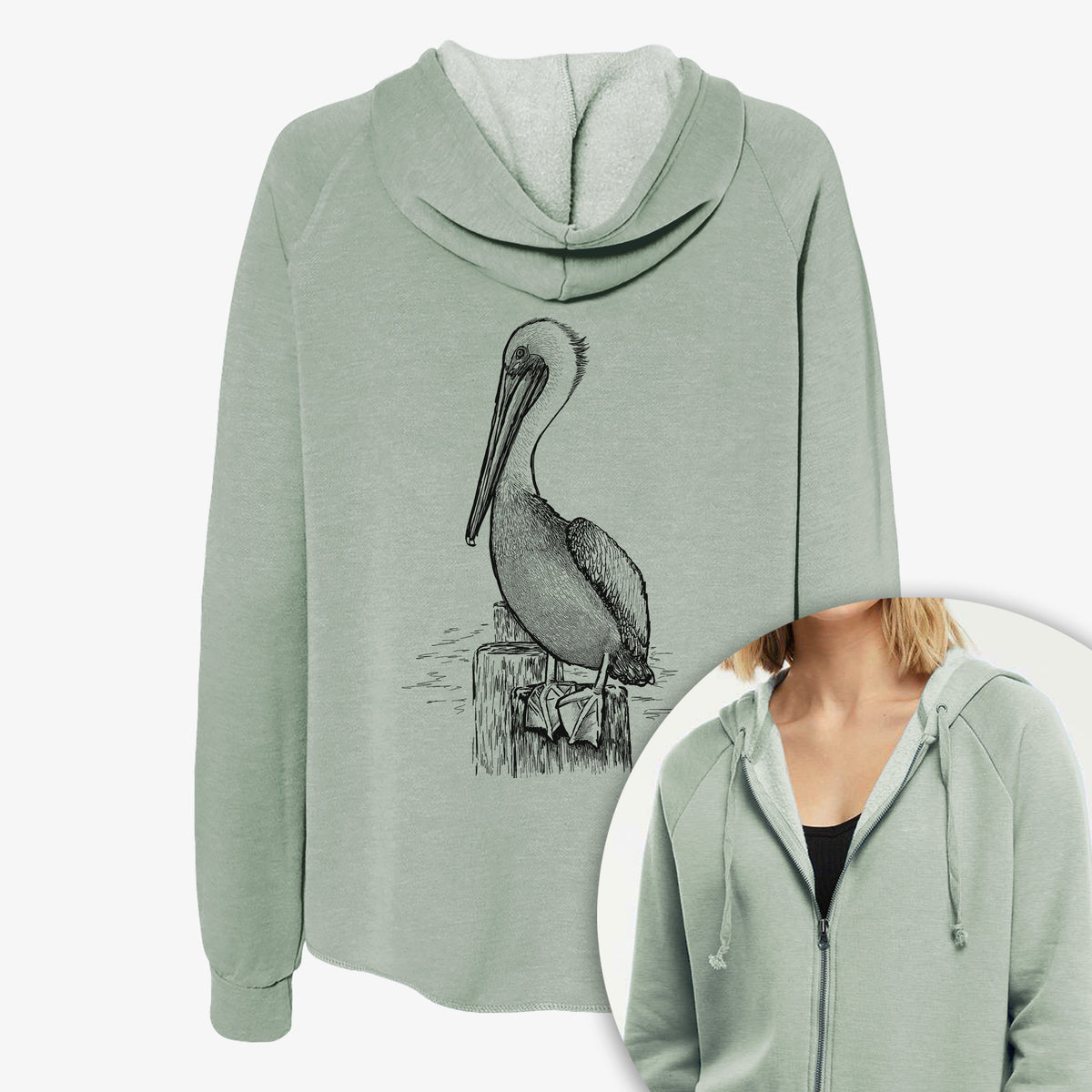 Women's Cali Wave zip-up sweatshirt printed with a detailed black ink illustration of a brown pelican perched on a wooden piling, with a close-up of the zipper.