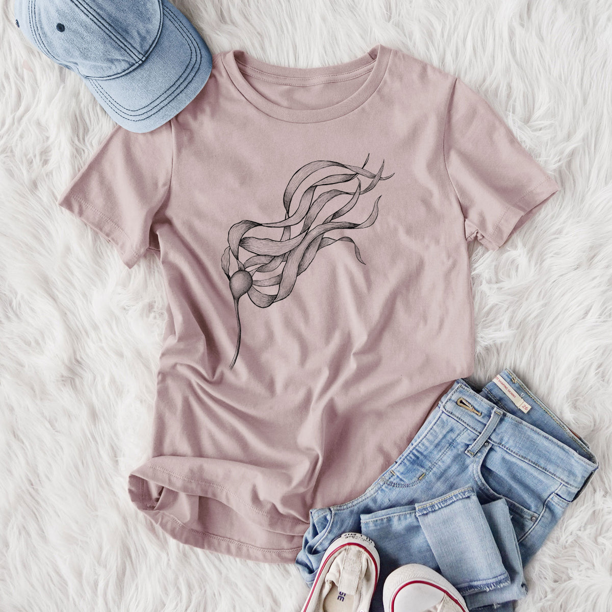Women's relaxed fit cotton t-shirt printed with a black ink line drawing of a strand of bull kelp with long flowing blades, styled flat on a white faux fur rug with jeans.