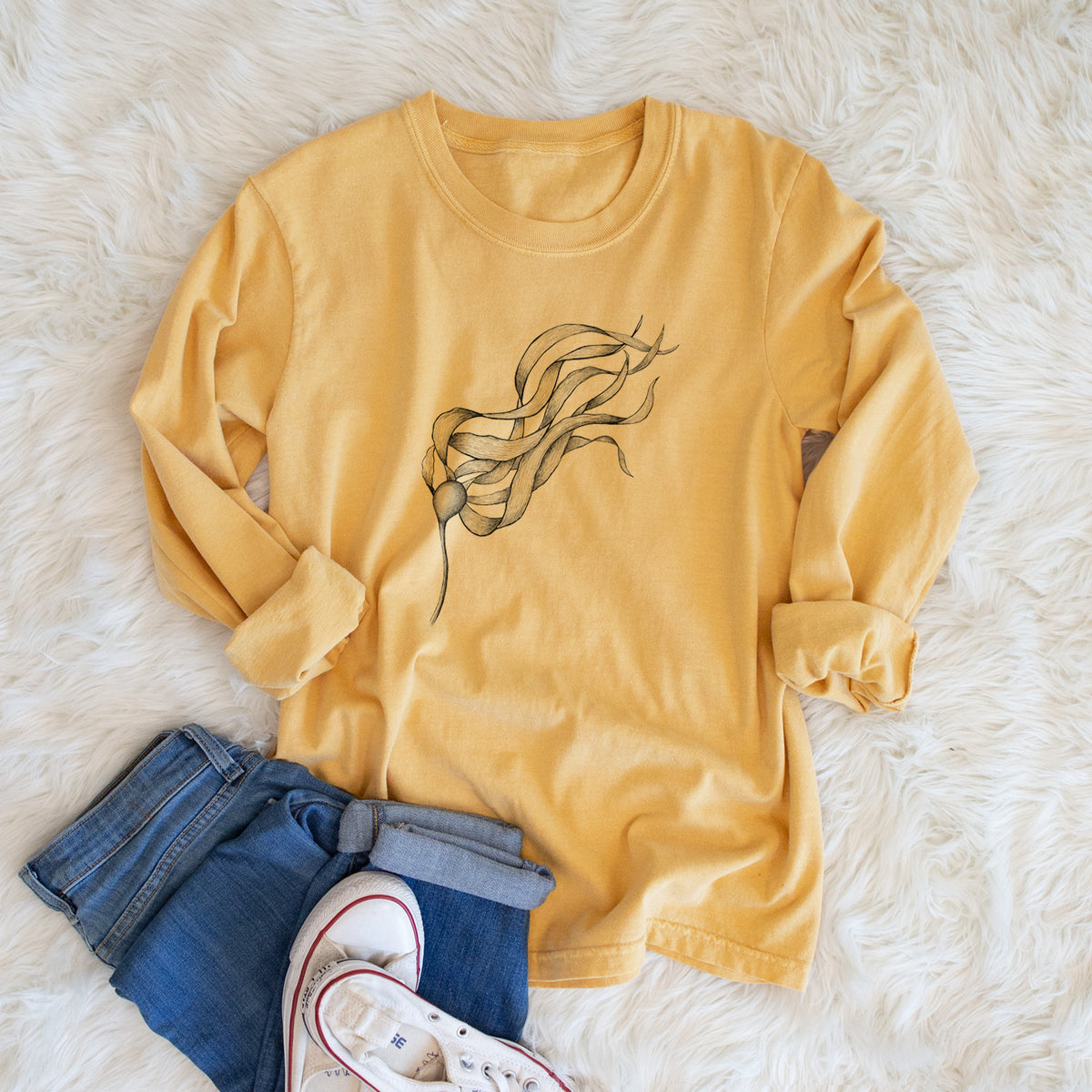Golden wheat yellow Comfort Colors long sleeve shirt printed with a black ink line drawing of a strand of bull kelp with long flowing blades, shown in a lifestyle photo.